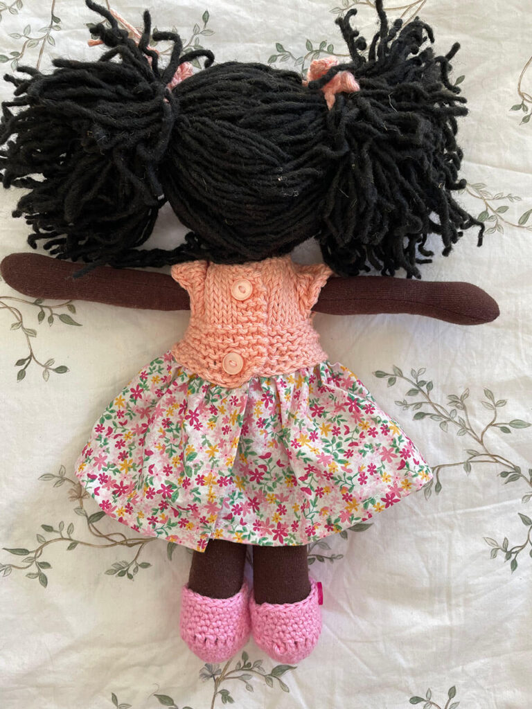 Muñeca pequeña morena con pelo color negro y vestido tejido color rosa